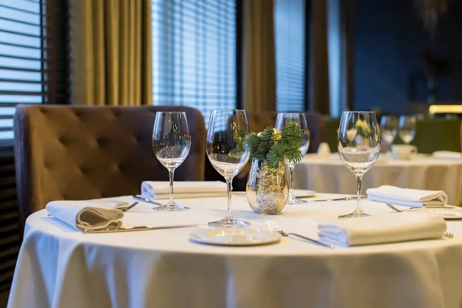 Sophisticated dining setup with polished wine glasses, white napkins, and a decorative centerpiece on a round table.